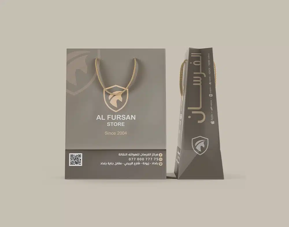 أكياس كرتونية بتصميم فاخر لشركة الفرسان للموبايلات في بغداد، تظهر الواجهة بشعار AL FURSAN STORE ومعلومات التواصل وQR مع عرض جانبي للكيس